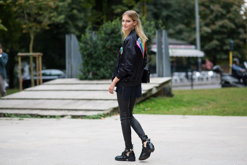 A blonde woman in a full black fall outfit consisting of shoes, pants, and a jacket