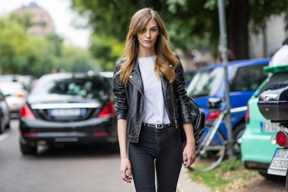 A dark blonde woman in a white shirt, black leather jacket and black pants