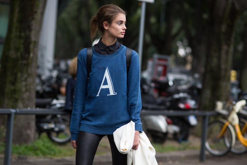 A brunette girl in a blue sweater with an "A" letter sign