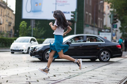 Girl running across the road in a white t-shirt and long blue skirt