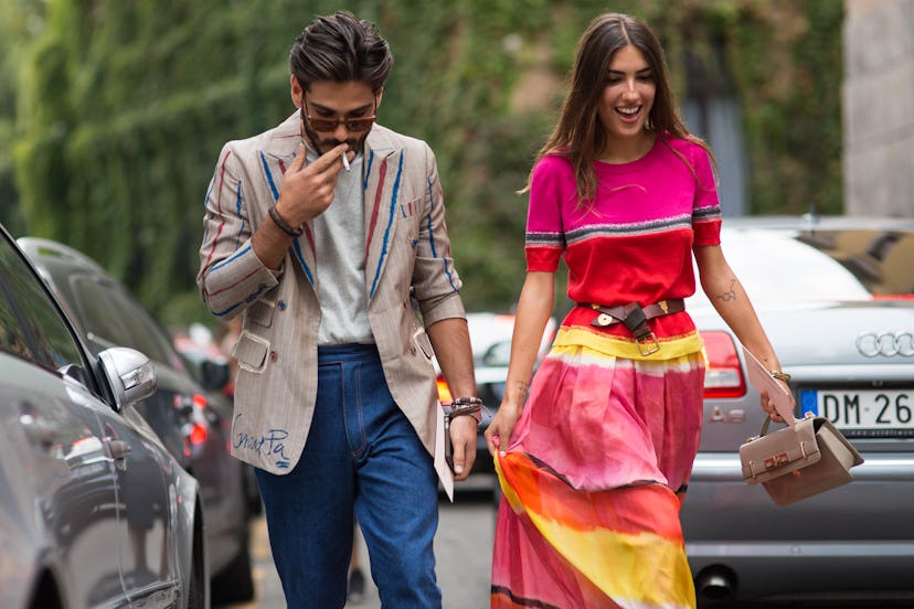 A girl wearing a colorful dress and a man wearing blue pants in combination with a beige blazer