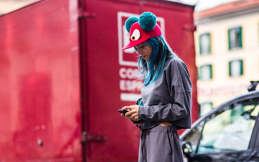 A girl with blue hair wearing a comfy, gray sweatsuit set, and a red baseball hat with big eyes and ...