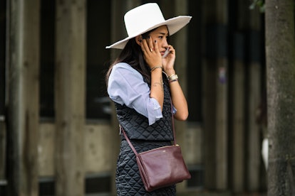 Peggy Gould wearing a white hat, blue button up, black vest with a matching skirt, and a burgundy pu...