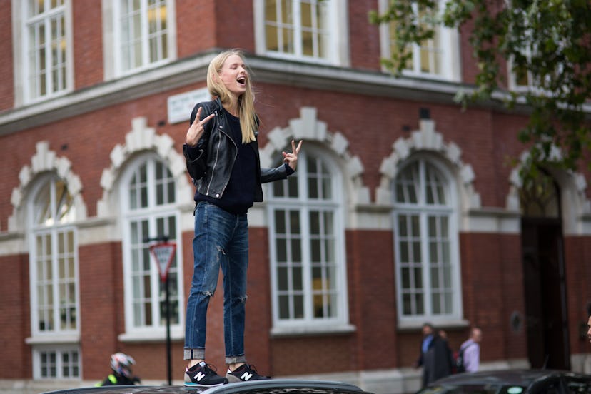 Lina Berg standing on a car and posing in a black leather jacket, black shirt, jeans, and black New ...