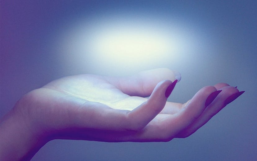 A hand with red nails holding an floating orb of light on the palm with a heavy blue filter in the c...