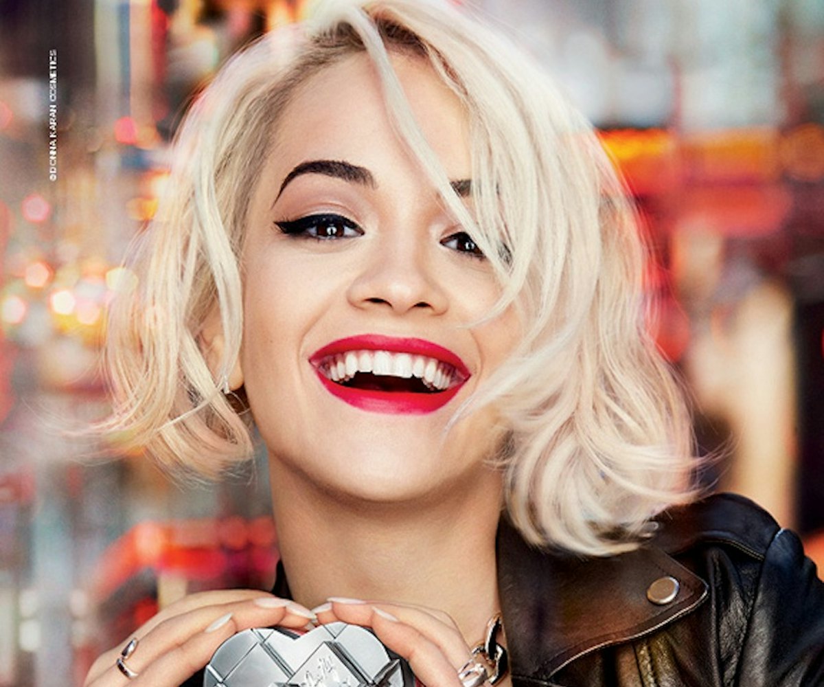 Rita Ora, with her blonde hair and red lipstick, smiling while holding a heart shaped MYNY scent by ...