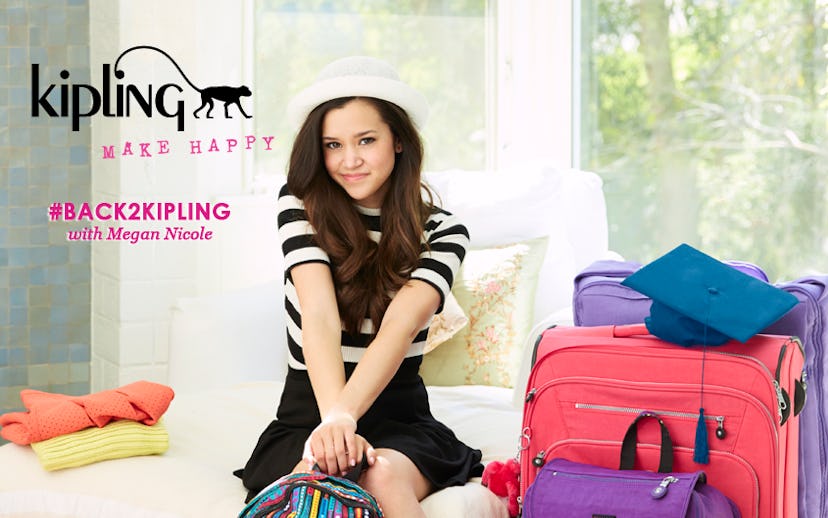 Megan Nicole wearing black-and-white clothes, sitting on a bed, and holding a Kipling backpack