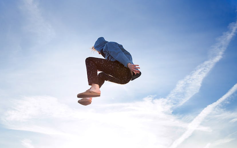 A man jumping up in a Victory Press blue hoodie and black printed jeans.