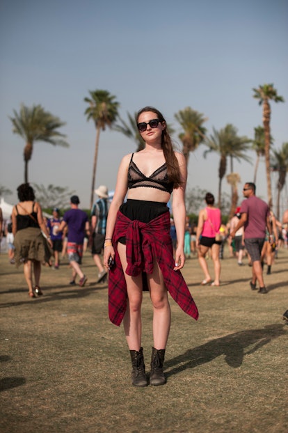 A woman in a black bra and shorts with a black-red checked shirt tied around her waist and black sun...