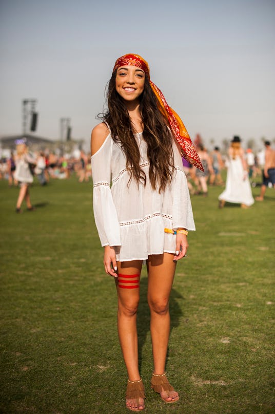 A woman in an off-white hippie dress with cut-out shoulder sections, an orange-red silk bandana, and...