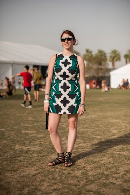 A woman in a short sleeveless black-white-green dress with an abstract floral print, black roman san...