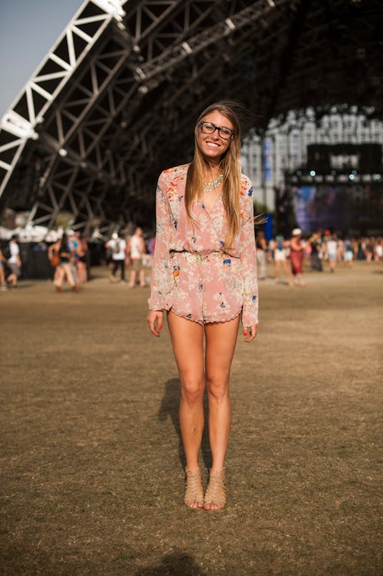 A woman in a long-sleeved pastel pink floral romper, glasses and beige short roman sandals