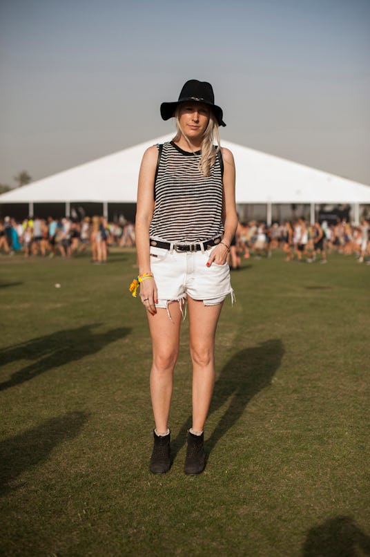 A woman in a semi-translucent black and white striped top, white denim shorts, and black hat and bla...