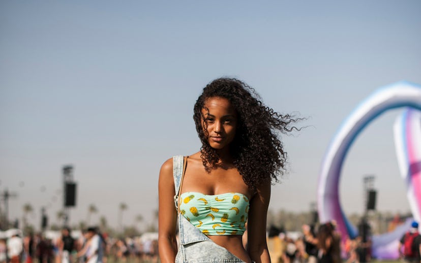 A woman in a blue denim romper with a green tube top with pineapple print and brown leather boots