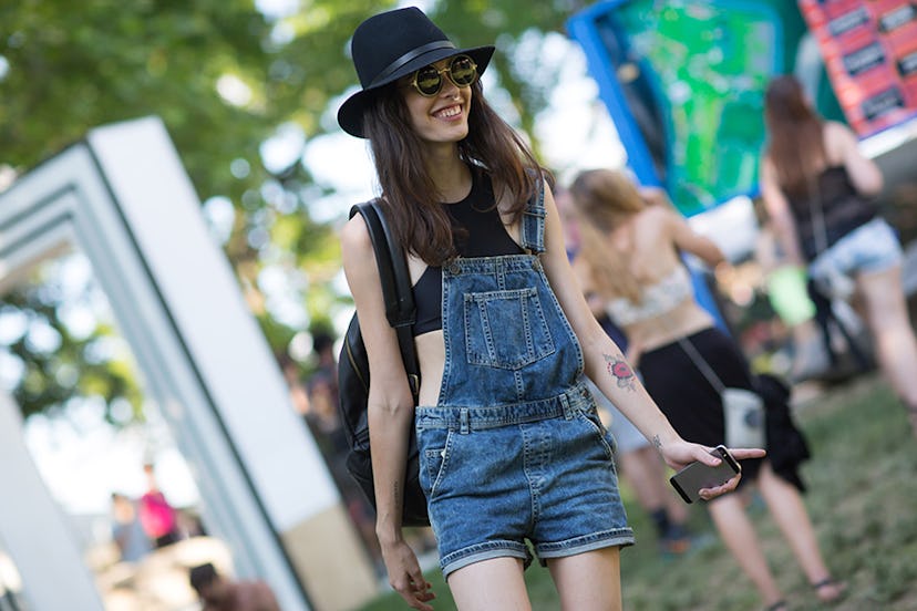 Carly Foulkes in a black hat, black top, denim overalls and sunglasses at Governors Ball