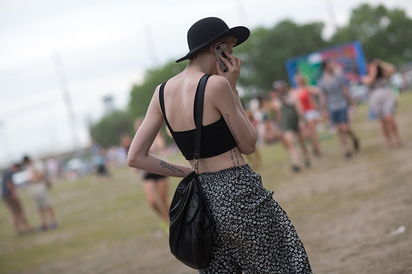 A model at Governors Ball in a black top and black floral pants 