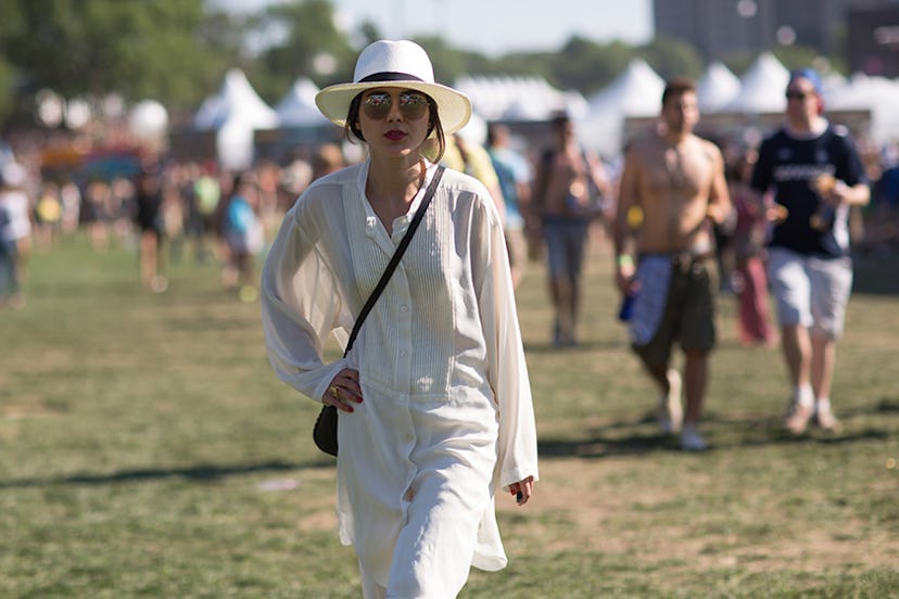A woman at Governors Ball in a long white button-up dress and a white hat 