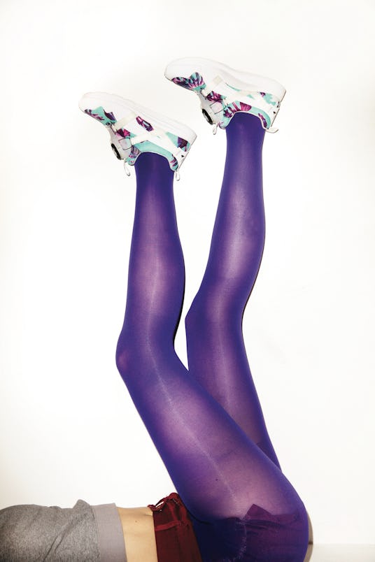 A model's legs up against a wall in purple tights and PUMA Disc Tropicalia sneakers 