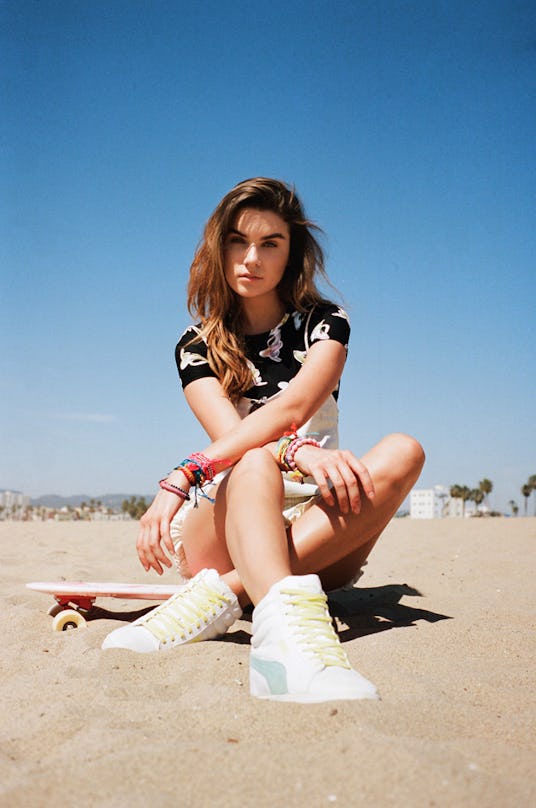 A model sitting on a skateboard at the beach in PUMA Classic Wedge Canvas sneakers 