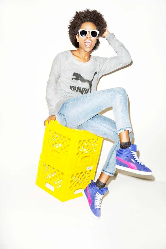 A model posing on a yellow crate in a grey PUMA  hoodie and PUMA Classic Wedge sneakers 