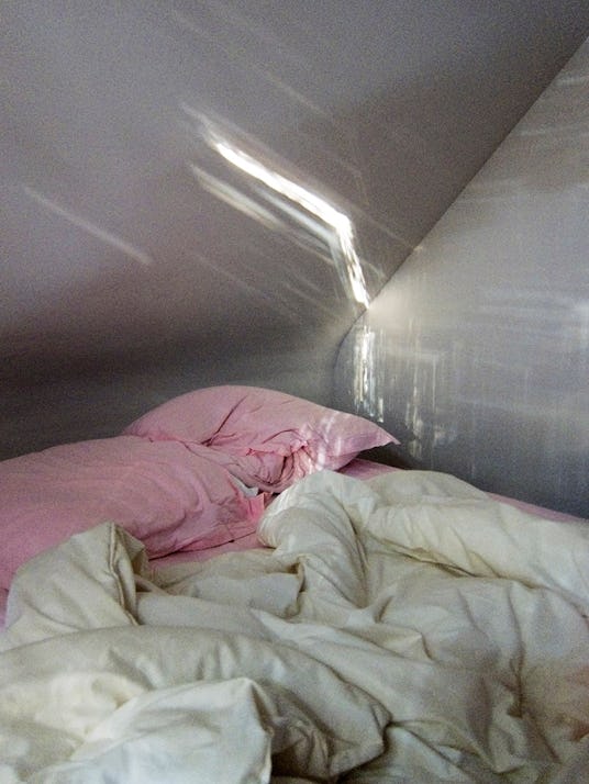 Close up of messy white bedding sheets and pink pillows