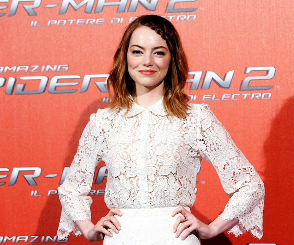 Emma Stone with red hair and a front braid posing in a white lace dress