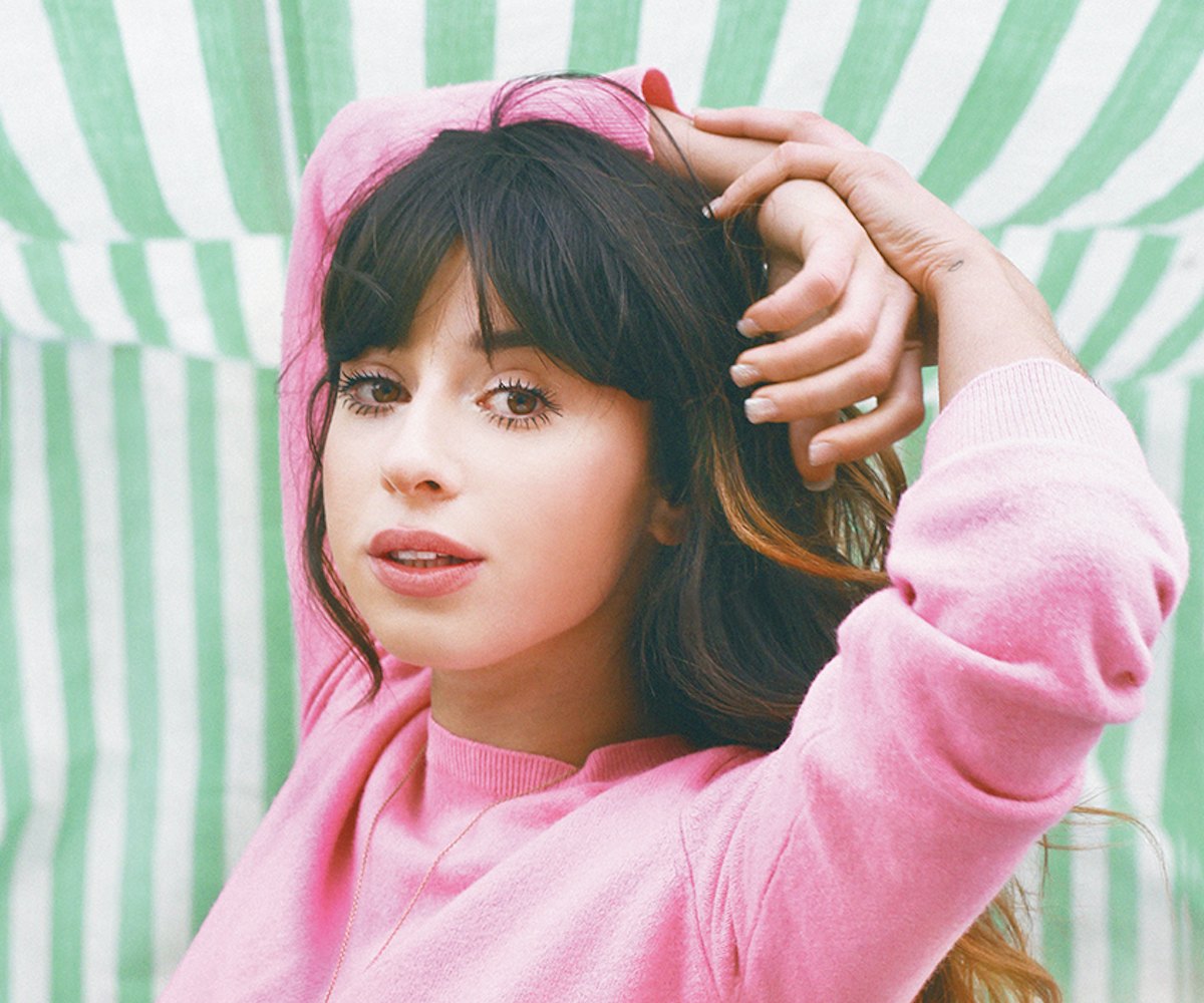 Foxes, an English singer that's part of March track compilation, posing in a pink sweater