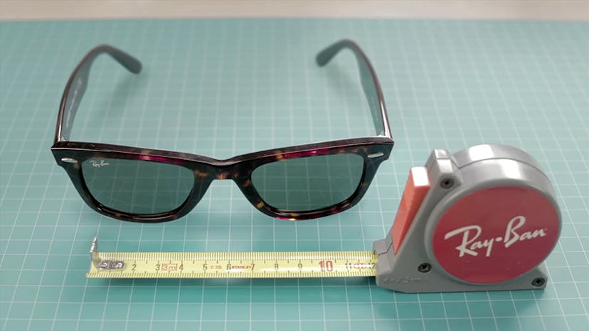 Brown Ray-Ban sunglasses lying next to a red Ray-Ban ruler