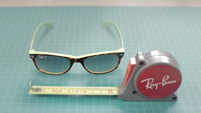 Yellow Ray-Ban sunglasses lying next to a red Ray-Ban ruler