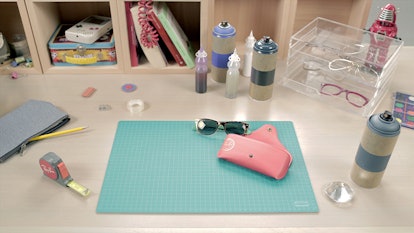 Table with Ray-Ban sunglasses, pink Ray-Ban sunglasses case, red Ray-Ban ruler and other products fe...