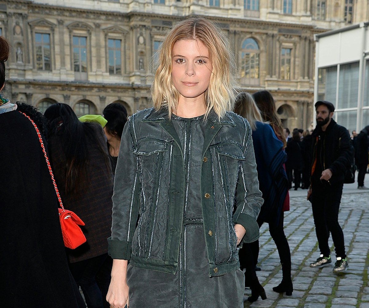 Kate Mara in a monochromatic, grey-washed jacket and dress combo, posing outside of the Louis Vuitto...