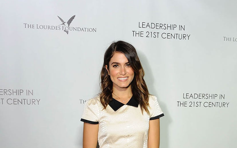 Actress Nikki Reed posing for a photo while wearing a simple white and black dress