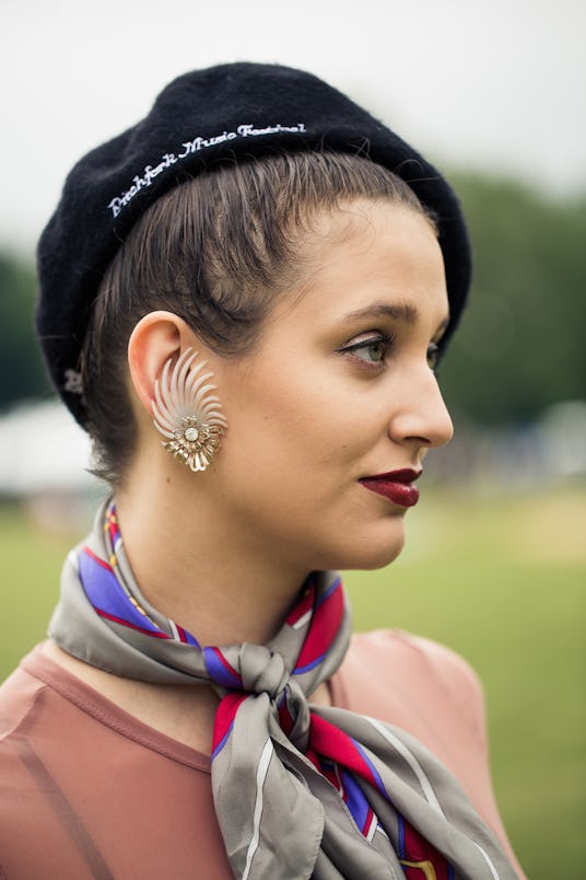 A woman wearing a black beret and a silk grey scarf with blue and red stripes