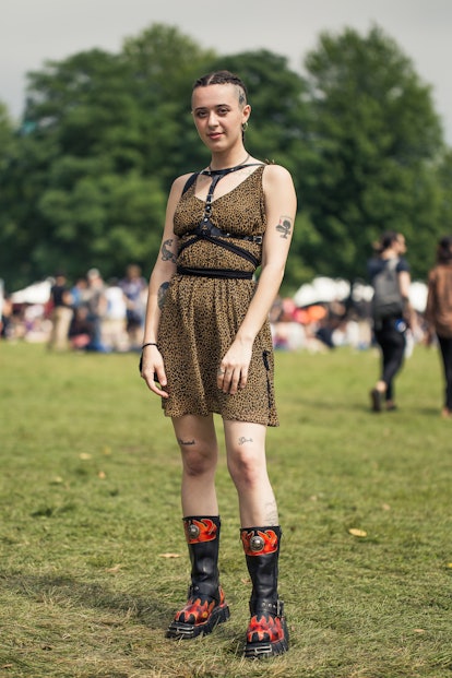  A girl with tattoos wearing a leopard print dress and black leather boots with flames on them