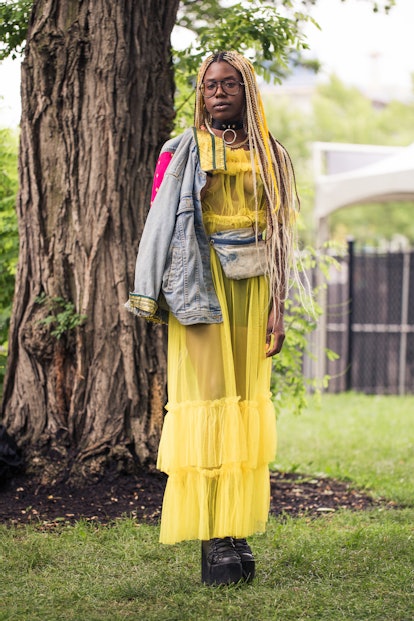 A girl wearing a yellow sheer tulle with a bondage-inspired choker and platform combat boots.