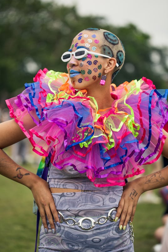  A girl in a gray tank and skirt, a tulle multicolored collar, blue smiley faces painted in her hair...