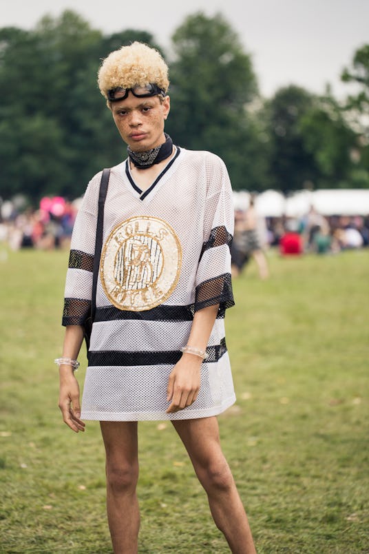 A festival-goer in a mesh jersey-like oversized striped shirt that says "Rolls Royce" on  it in gold...