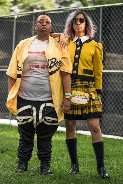 Two friends: one in a yellow baseball jersey, while the other is in a yellow blazer and skirt & an A...