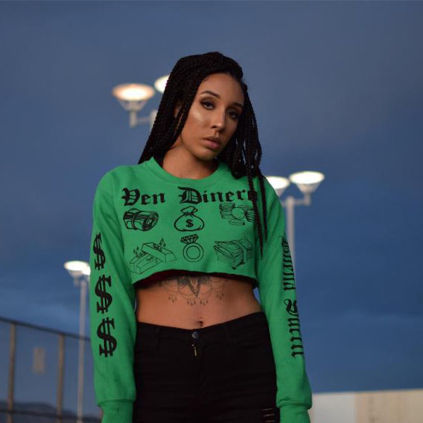 A model wearing a green cropped long-sleeve and black pants by Ella Loca 