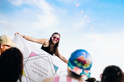 A woman standing above a crowd and holding a sign that says "festival squad" at Governor's Ball