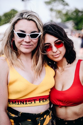 Two friends at Governor's Ball: one in a red cropped tank and and red sunglasses, the other in a yel...