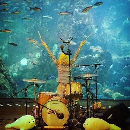 Lelah Maupin sitting next to drums on front of an aquarium