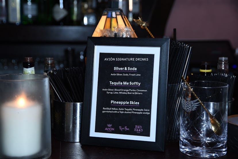 Menu of Avion cocktails at Lauren Jauregui's Nylon party, next to a candle and a glass with stirring...