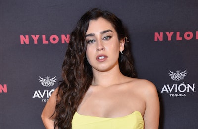 Lauren Jauregui posing at New York Fashion Week party, in front of Nylon banner, at a Rose bar.