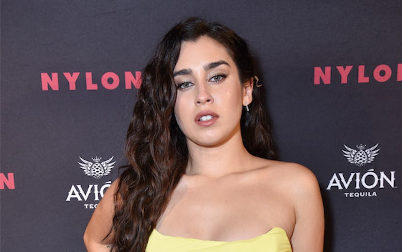 Lauren Jauregui posing at New York Fashion Week party, in front of a Nylon banner