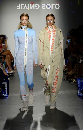 Two models walking the Flying Solo runway in Monosuit, one is in a blue jumpsuits and the other in a...