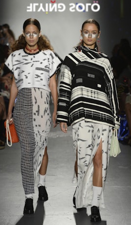 Two models in the Flying Solo show wearing Adi Yair: a blouse and semi-grey, semi-beige skirt, and a...