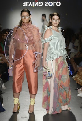 Two models in the Flying Solo show in C'est D by Doyeon Yoni Yu: a ruffled top and silk pants and a ...