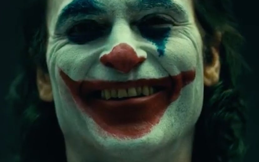 Joaquin Phoenix wearing full Joker makeup and smiling