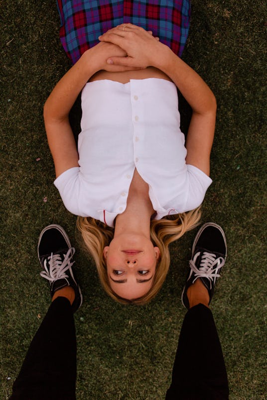 Katelyn Tarver lying on the ground looking to the left side surrounded by someone's legs wearing Van...